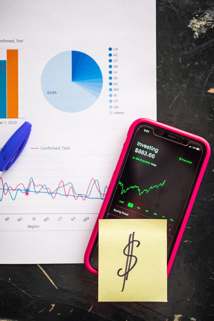 The Art of Drawing Readers In: Your attractive post title goes here Smartphone displaying stock market data alongside financial charts and a dollar sign note.